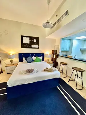 a large bedroom with a blue bed and a kitchen at Charming spacious studio apartment in the heart of JBR By SWEET HOMES in Dubai