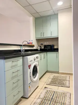 a kitchen with green cabinets and a washer and dryer at Charming spacious studio apartment in the heart of JBR By SWEET HOMES in Dubai