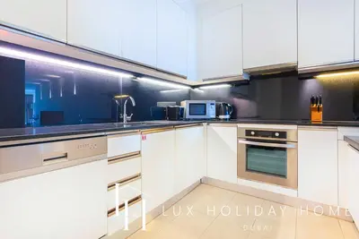 a kitchen with white cabinets and a microwave at LUX The JW Marina Suite in Dubai