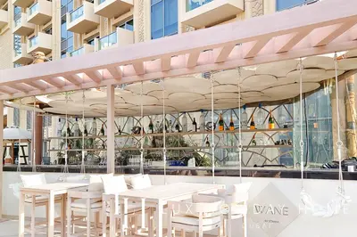a restaurant with white tables and chairs in front of a building at LUX The JW Marina Suite in Dubai