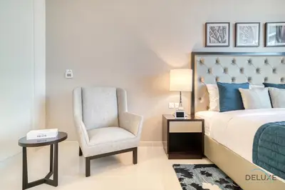 a bedroom with a king sized bed and a chair at Lively Studio at DAMAC Celestia A Dubai South by Deluxe Holiday Homes in Dubai