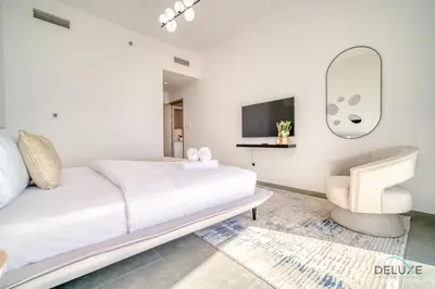 a white bedroom with a bed and a chair at Cosmopolitan 2BR at Stella Maris Dubai Marina by Deluxe Holiday Homes in Dubai
