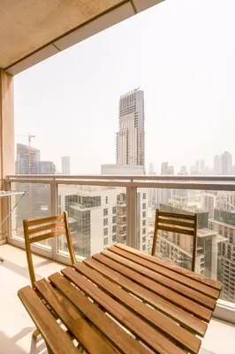 a balcony with a wooden bench and two chairs at INA Homes-Residences Tower 7 Full Burj Khalifa & Fountain Views in Dubai