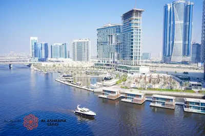 a boat in a river in a city with tall buildings at Al Ashrafia Saray Marvelous 1 BR - Damac Maison - Canal View in Dubai