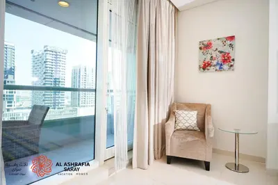 a living room with a chair and a large window at Al Ashrafia Saray Marvelous 1 BR - Damac Maison - Canal View in Dubai