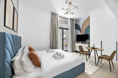 a living room with a bed and a table with chairs at Silkhaus brand new studio in Belgravia Heights, JVC in Dubai