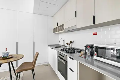 a white kitchen with a counter and a table at Silkhaus brand new studio in Belgravia Heights, JVC in Dubai