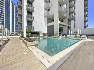 a swimming pool in front of a building at Silkhaus brand new studio in Belgravia Heights, JVC in Dubai