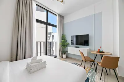 a white room with a bed and a table and chairs at Silkhaus modern studio in the heart of vibrant JVC in Dubai
