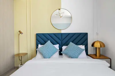 a bedroom with a bed with a blue headboard and a mirror at Silkhaus modern studio in the heart of vibrant JVC in Dubai