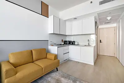 a living room with a couch and a kitchen at Silkhaus new stylish studio in JVC Luma21 in Dubai