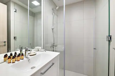 a white bathroom with a sink and a shower at Silkhaus new stylish studio in JVC Luma21 in Dubai