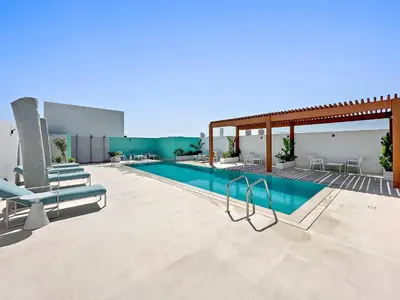a swimming pool with lounge chairs and a patio at Silkhaus new stylish studio in JVC Luma21 in Dubai