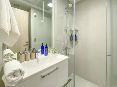 a white bathroom with a sink and a shower at Trophy - Urban Escape Suite in Dubai