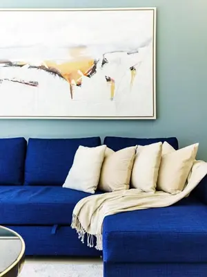 a blue couch in a living room with a picture on the wall at Downtown Charming Condo Close to Dubai Mall in Dubai