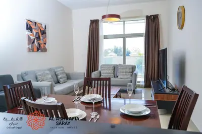 a living room with a table and chairs and a couch at Alashrafia Saray 2BR apartment in Sport City in Dubai