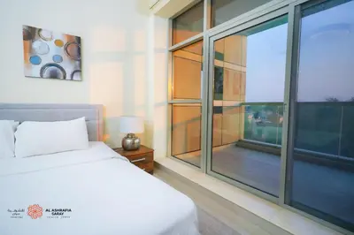 a bedroom with a bed and a large window at Alashrafia Saray, Lovely 2 BR apartment in Sport city in Dubai