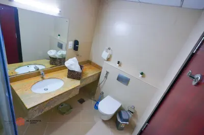 a bathroom with a sink and a toilet and a mirror at Alashrafia Saray, Lovely 2 BR apartment in Sport city in Dubai