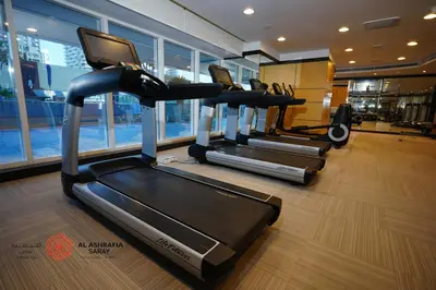 a gym with three tread machines in a room at Alashrafia Saray, Lovely 2 BR apartment in Sport city in Dubai