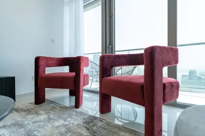 two red chairs sitting in front of a window at La Dolce Vita Residence by Suiteable Interiors in Dubai