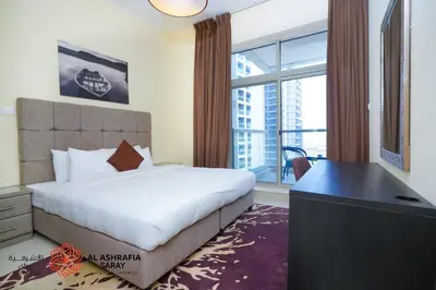 a bedroom with a bed and a desk and a window at Alashrafia Saray, Charming 1BR apartment in Sport City in Dubai