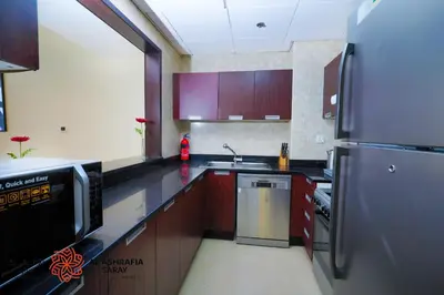 a kitchen with a stainless steel refrigerator and wooden cabinets at Alashrafia Saray, Charming 1BR apartment in Sport City in Dubai