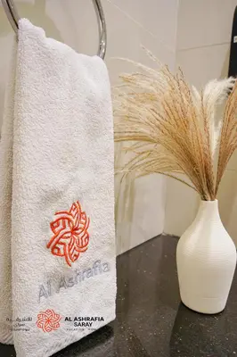 a towel sitting next to a vase with a plant at Al Ashrafia Saray - Extraordinary Studio in Canal View in Dubai