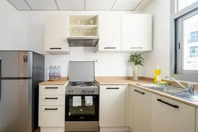 a kitchen with white cabinets and a stove at Exclusive Designer Studio by Marina, Beach & Mall in Dubai