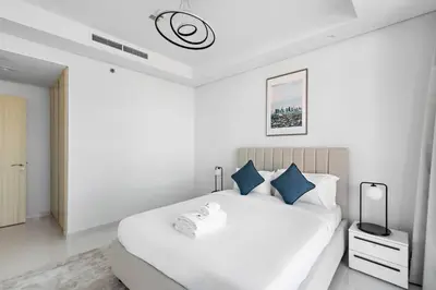 a white bedroom with a large white bed with blue pillows at StoneTree - Paramount Tower Hotel&Residences 3 BR - Sea View and Infinity Pool in Dubai
