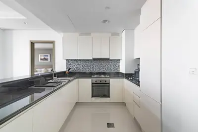a large white kitchen with white cabinets and appliances at StoneTree - Paramount Tower Hotel&Residences 3 BR - Sea View and Infinity Pool in Dubai
