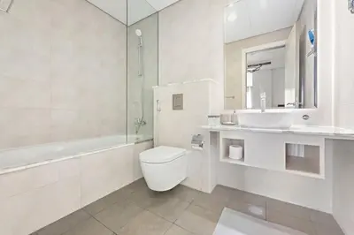 a white bathroom with a toilet and a sink at StoneTree - Paramount Tower Hotel & Residences 2 BR - Infinity Pool & Stunning View in Dubai