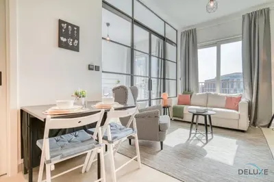 a living room with a table and chairs and a couch at Jovial 1BR at Collective Tower 2 Mohammed Bin Rashid City by Deluxe Holiday Homes in Dubai