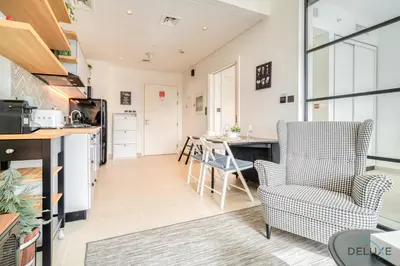 a kitchen and living room with a table and chairs at Jovial 1BR at Collective Tower 2 Mohammed Bin Rashid City by Deluxe Holiday Homes in Dubai