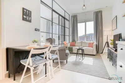 a living room with a table and chairs and a couch at Jovial 1BR at Collective Tower 2 Mohammed Bin Rashid City by Deluxe Holiday Homes in Dubai