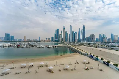 a beach with chairs and umbrellas in front of a city at Maison Privee - Deluxe 3BR Apt with Dubai Marina Vws & Beach Access in Dubai