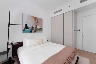 a bedroom with a white bed and a painting on the wall at Maison Privee - Deluxe 3BR Apt with Dubai Marina Vws & Beach Access in Dubai