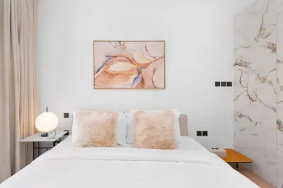 a bedroom with a white bed and a painting on the wall at Maison Privee - Deluxe 3BR Apt with Dubai Marina Vws & Beach Access in Dubai
