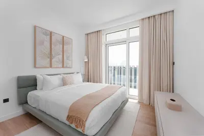 a white bedroom with a large bed and a window at Maison Privee - Deluxe 3BR Apt with Dubai Marina Vws & Beach Access in Dubai
