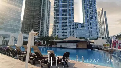 a pool with chairs and umbrellas in front of tall buildings at LUX The JBR Beach Sea View Suite in Dubai