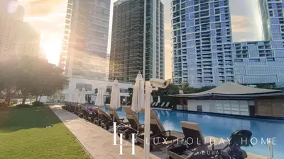 a pool with chairs and umbrellas in front of tall buildings at LUX The JBR Beach Sea View Suite in Dubai