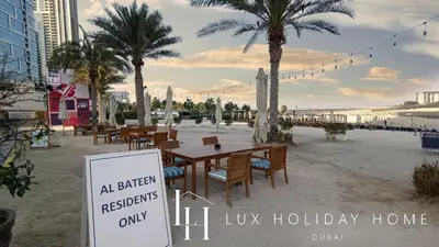 a sign on a beach with tables and palm trees at LUX The JBR Beach Sea View Suite in Dubai