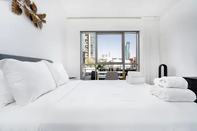 a white bedroom with a large white bed with white pillows at Stylish and Central 1 BD in Downtown Dubai in Dubai