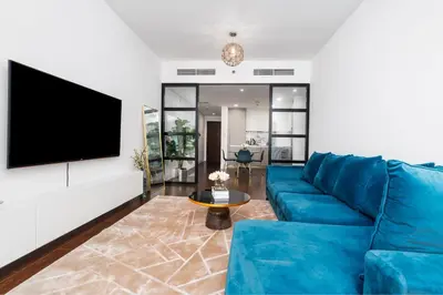 a living room with a blue couch and a flat screen tv at Stylish and Central 1 BD in Downtown Dubai in Dubai