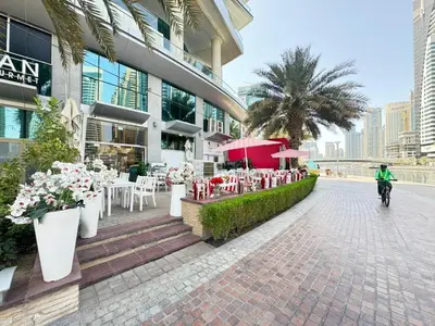 a person riding a bike past a building with tables and chairs at Spacious studio apartment in Dubai Marina close to metro and beach in Dubai