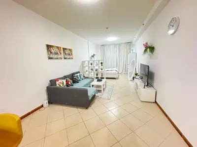 a living room with a couch and a tv at Spacious studio apartment in Dubai Marina close to metro and beach in Dubai
