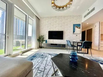a living room with a television and a table and chairs at Elegant & Chic 2bedroom balcony Creek Waterfront in Dubai