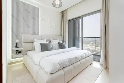 a white bedroom with a large white bed and a window at Cozy 1bdr 10' from Burj Khalifa in Dubai
