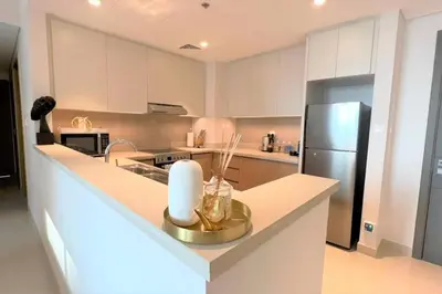 a kitchen with white cabinets and a stainless steel refrigerator at Modern & Chic Waterfront 2bed balcony Dubai Creek in Dubai
