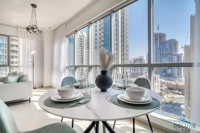a dining room with a table and chairs and a large window at Glamorous 1BR at Residences 5 Downtown Dubai by Deluxe Holiday Homes in Dubai