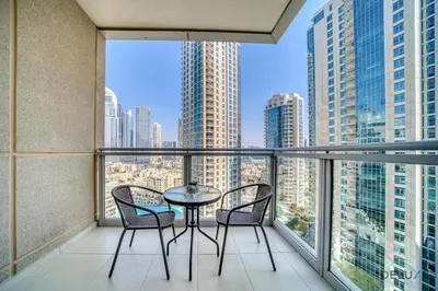 a balcony with a table and chairs and a view of the city at Glamorous 1BR at Residences 5 Downtown Dubai by Deluxe Holiday Homes in Dubai